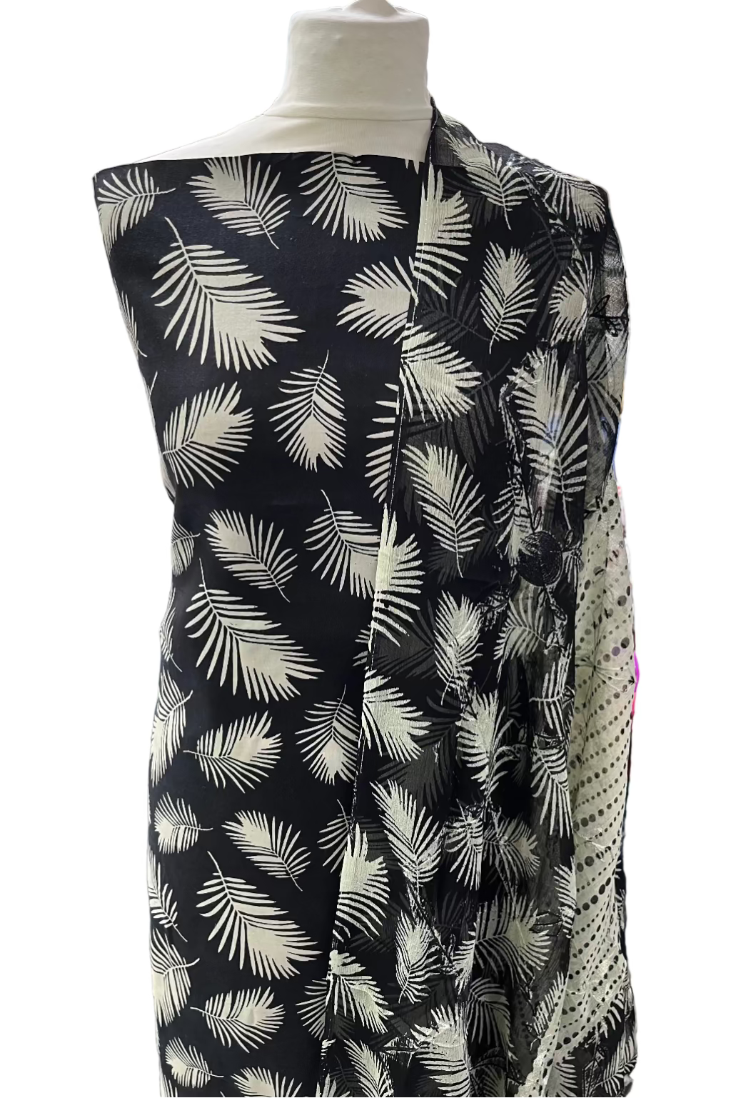 Mannequin wearing a black dress with white leaf pattern in a store setting