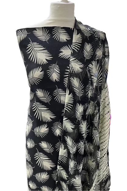 Mannequin wearing a black dress with white leaf pattern in a store setting