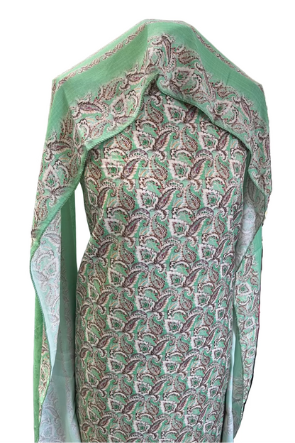 Green patterned fabric draped over a stand in a store setting