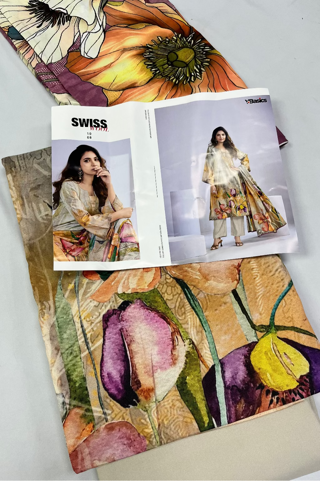Open magazine showing fashion design with colorful floral patterns on a white surface