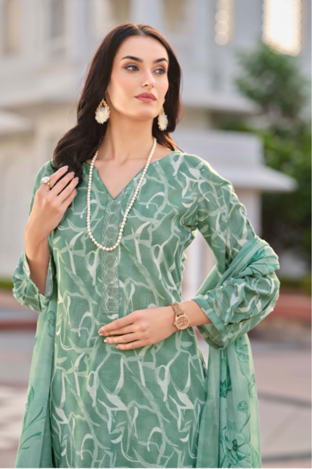 Woman wearing a green traditional outfit with a white building in the background