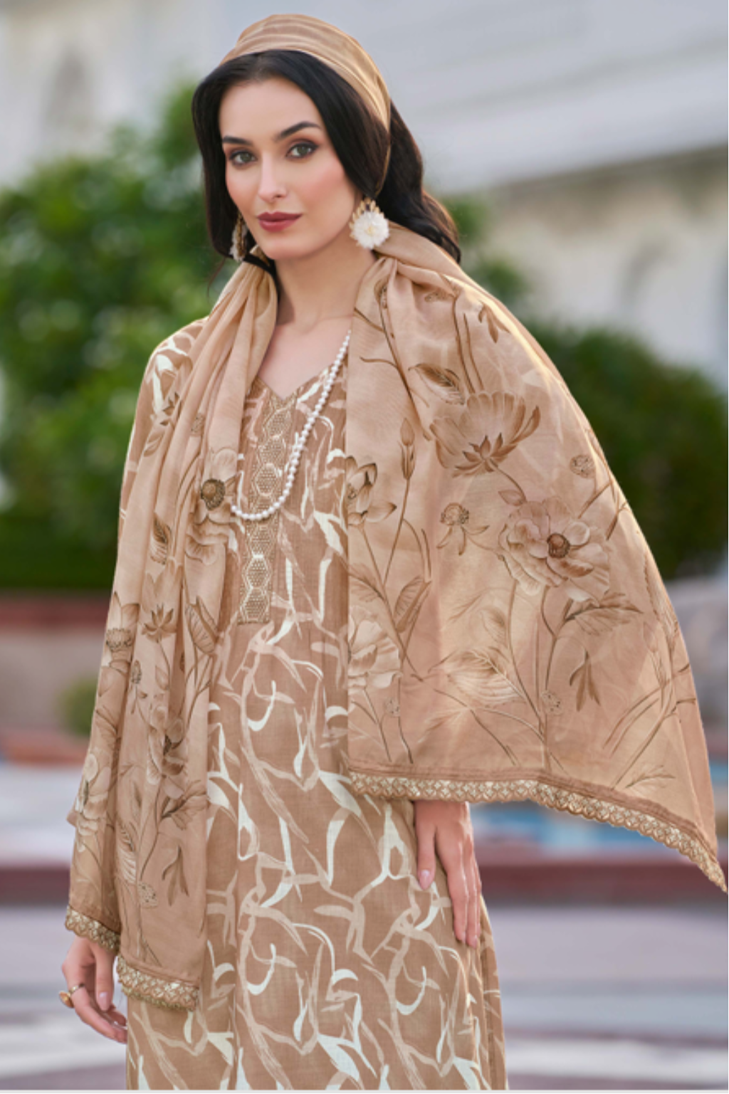 Woman in a beige traditional outfit with a building in the background