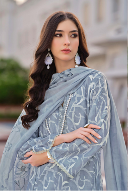 Woman wearing a light blue embroidered outfit in front of a building.