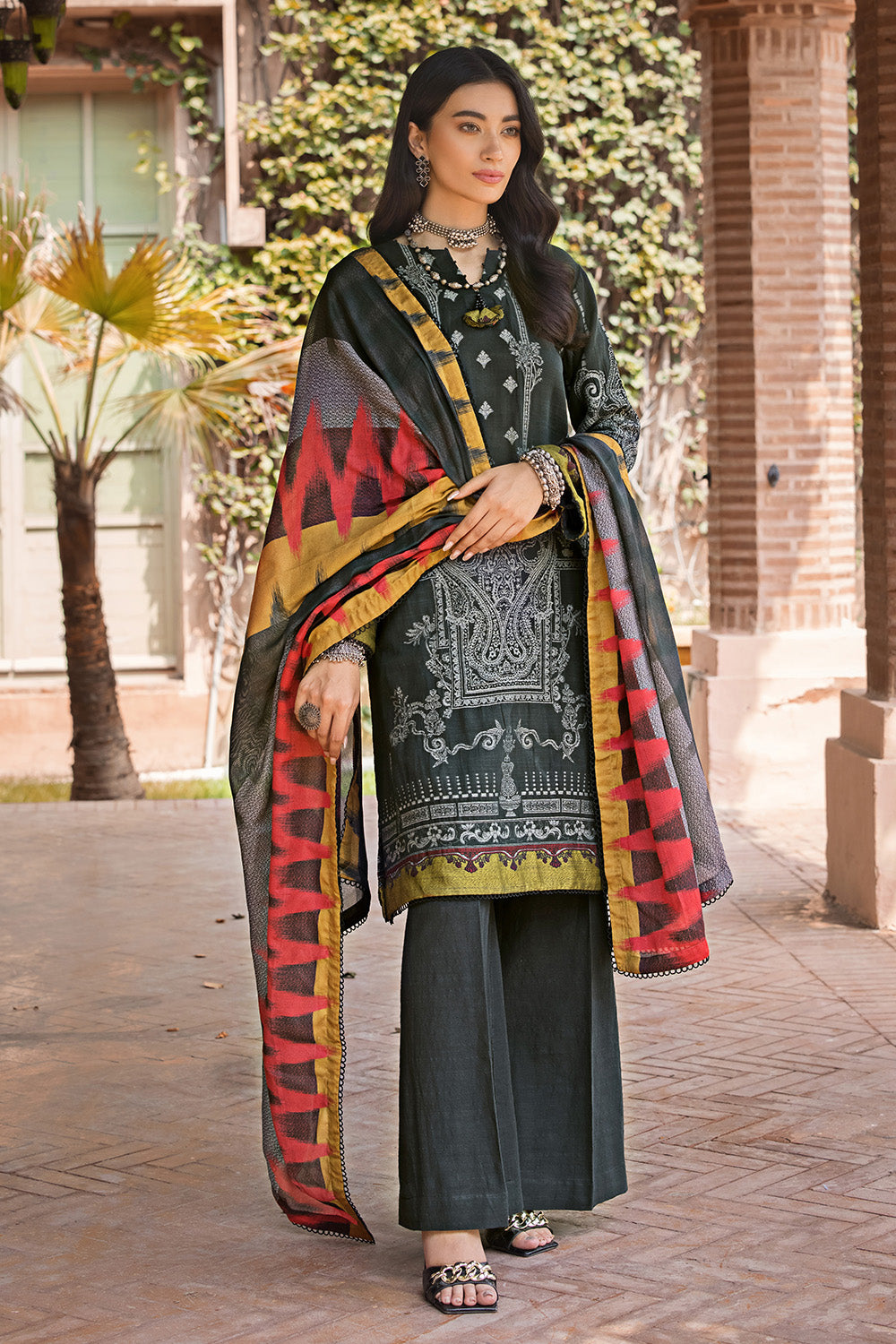 A woman wearing a traditional salwar kameez suit with a digital printed cotton net dupatta in red, yellow, and green colors, and a black khaddar jacquard shirt.