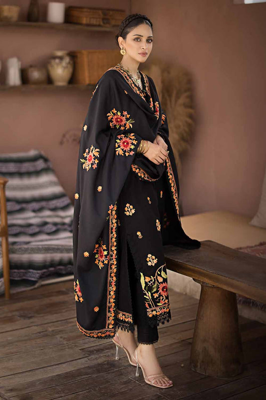A woman wearing a black traditional salwar kameez suit with embroidered floral designs, featuring a dupatta, shirt, and dye-printed trouser.